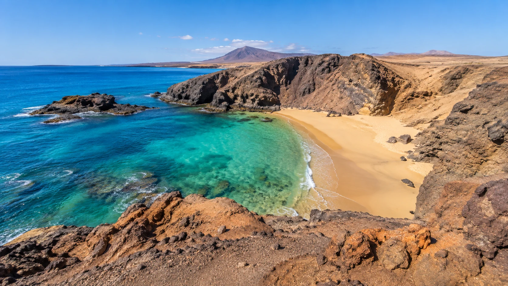 Golden beach and turquoise water along a volcanic coastline in the eastern Canary Islands