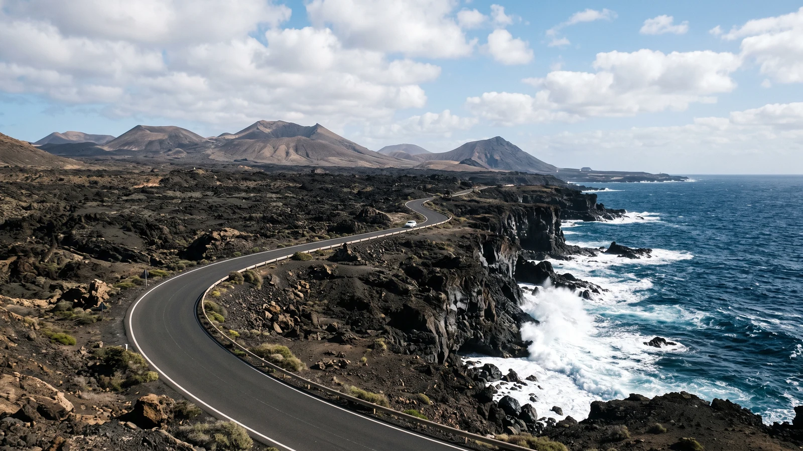 Winding road through dark volcanic terrain beside the Atlantic coast